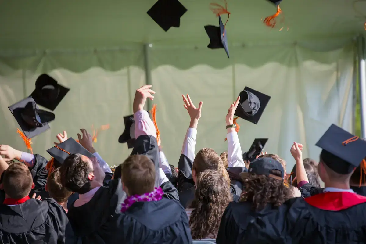 A group of graduates tossing mortarboards in the air celebrating completion of advanced online PhD classes